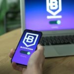 Person uses a blockchain application on smartphone, mirrored on laptop screen.